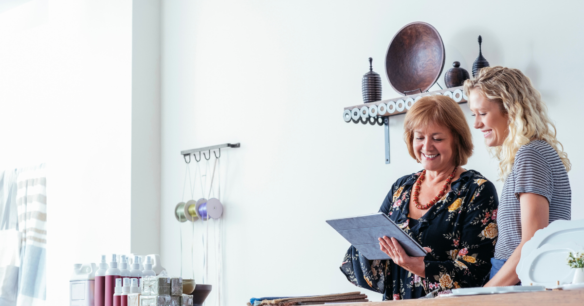 Photograph of two women behind a store counter on their tablet. Photo is to illustrate small business owners following the new federal requirement for beneficial ownership information reporting.