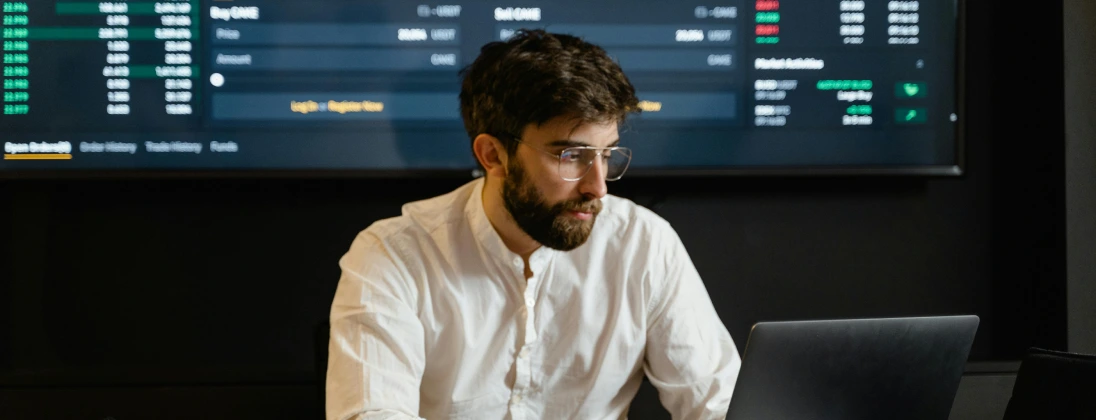 Image of a man working at a computer with a screen behind him to embody an employee with equity compensation looking for information on an IPO.